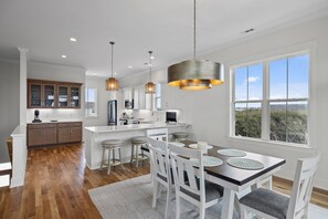 A modern kitchen with white cabinetry, a central island, and pendant lighting. - Oceanside Home with Elevator in Atlantic Beach, NC! (Once Upon a Tide) (Atlantic Beach)