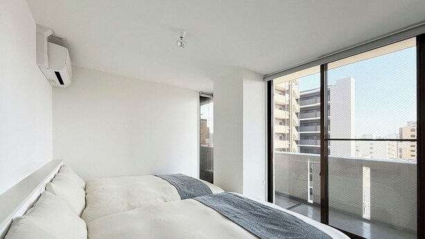 Een moderne slaapkamer met een groot bed, een plafondventilator en stadszicht door een groot raam.