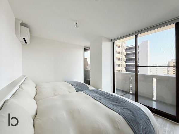 Un dormitorio moderno con una cama grande, un ventilador de techo y vistas a la ciudad a través de un ventanal.