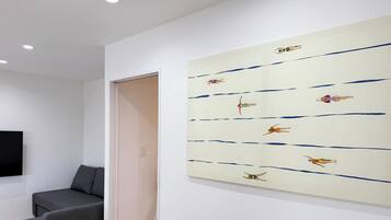 A room with a large abstract painting on the wall, a gray sofa, and a closed door.