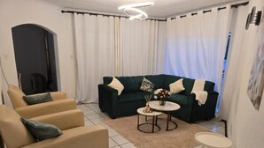 A living room with a sofa, two armchairs, a coffee table, and a small side table. - Room-charming Lodge Room in Sandton With (Johannesburg)