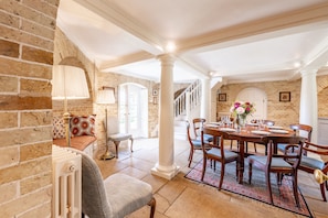 A dining area with a brick wall, a white radiator, a bench, and a table set for six with chairs. - A Duke's spectacular grand folly -The Temple (Bury St Edmunds)