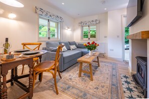 A cozy living room with a sofa, wooden chairs, a dining table, and a fireplace.