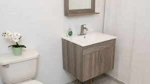 Ein Badezimmer mit Toilette, Waschbecken, Spiegel und Duschvorhang.
