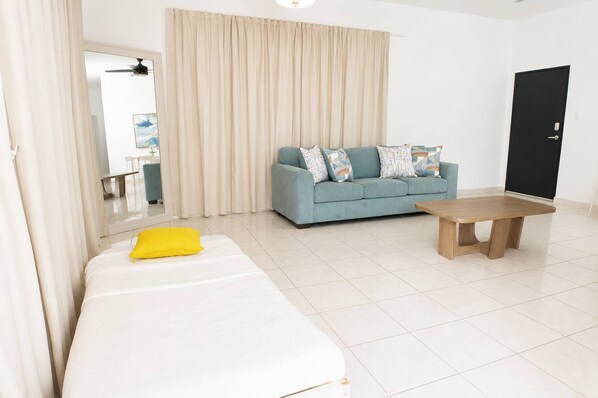 Una habitación con una cama, un sofá, una mesita de café y una puerta.