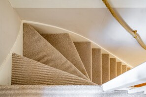 Eine Wendeltreppe mit strukturierter Wand und weißer Handlauf.