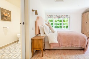 Ein Schlafzimmer mit Bett, Nachttisch und einem Fenster mit Blick auf Grünflächen.