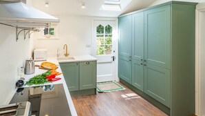 A modern kitchen with a skylight, wooden flooring, and green cabinets. - Exceptional woodland cottage in Constable Country - Cosgrove Lodge (Colchester)