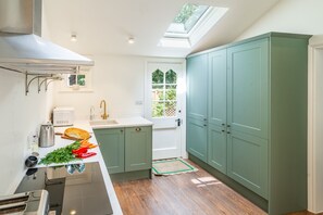 Eine moderne Küche mit Oberlicht, Holzboden und grünen Schränken.