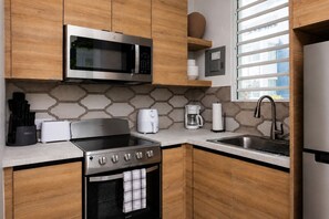 Eine moderne Küche mit Mikrowelle aus Edelstahl, einem Backofen, einem Kochfeld und einer Spüle.