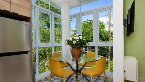 Una cucina con frigorifero, un tavolo da pranzo con sedie e una finestra vista sul verde.