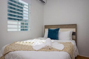 Ein Hotelzimmer mit Bett, Fenster und Blick auf ein Gebäude.