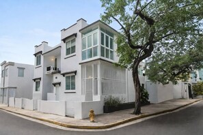 Ein modernes, zweistöckiges Gebäude mit weißer Fassade, großen Fenstern und einem Baum davor.