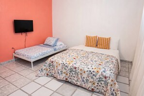 Ein Schlafzimmer mit einem Bett, einem an der Wand montierten Fernseher und einem Fenster.