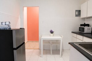 Eine kompakte Küche mit Kühlschrank, Mikrowelle und einem kleinen Esstisch mit Stühlen.