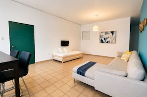 Ein Zimmer mit einem Bett, einem Schlafsofa, einem Fernseher und einem Essbereich.
