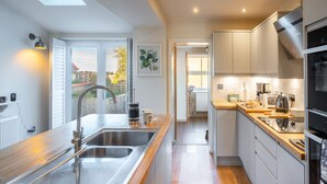 Eine moderne Küche mit Spüle aus Edelstahl, Arbeitsplatte aus Holz und weißen Schränken.