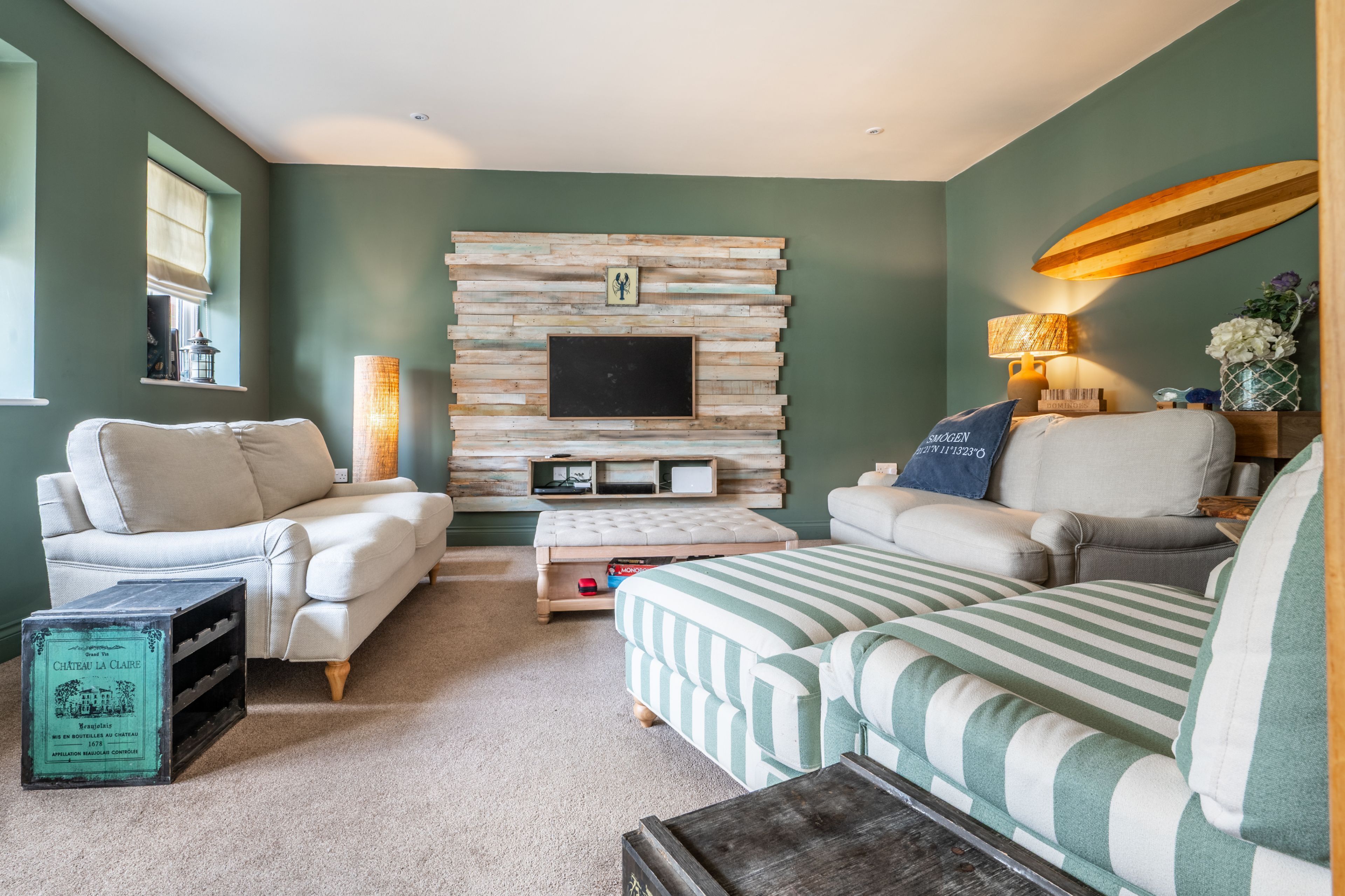 A living room with a stone wall, a flat-screen TV, a sofa, a coffee table, and a lamp.