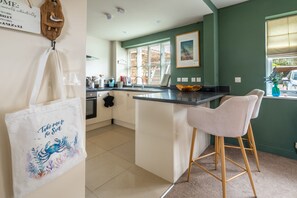 A kitchen with a central island, a bar stool, and a view of the outside. - Sea Horse Stables, Overstrand, Norfolk (Overstrand)