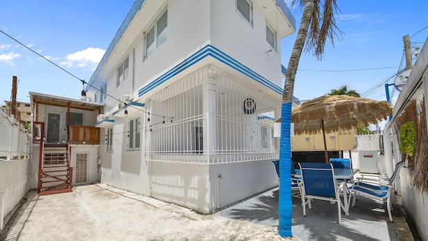 A white building with blue trim, a gated entrance, and outdoor seating. - Cozy San Juan Stay | Near Airport & Old San Juan (San Juan)