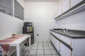 Eine kleine Küche mit weißen Schränken, einer Mikrowelle, einem Kühlschrank und einem Spülbecken.