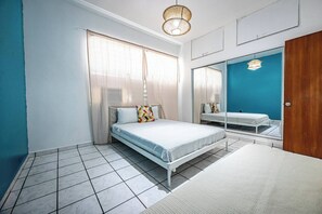 Ein Schlafzimmer mit einem Bett, einem Spiegel, einem Kleiderschrank und einer Pendelleuchte.