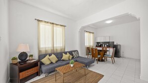 A living room with a sofa, coffee table, and a dining area with chairs and a table. - Cozy Family Apartment at San Juan (San Juan)