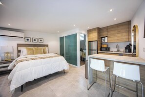 Ein modernes Hotelzimmer mit Bett, einer Küchenzeile und einer Bar.