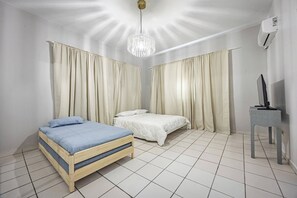 A bedroom with two beds, a TV, and an air conditioner. - Budget Friendly Apt with 2 Balconies Near Beach (San Juan)