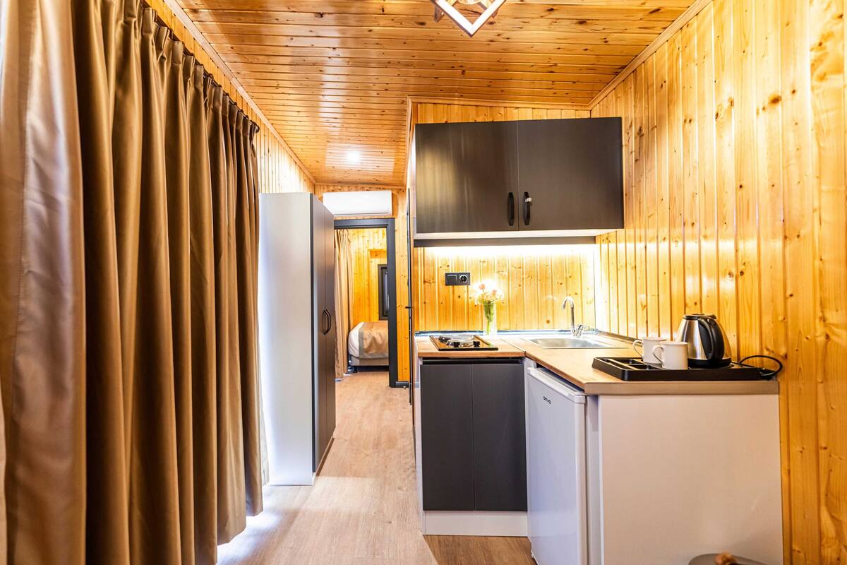 A compact kitchen with wooden walls, a built-in oven, and a sink.