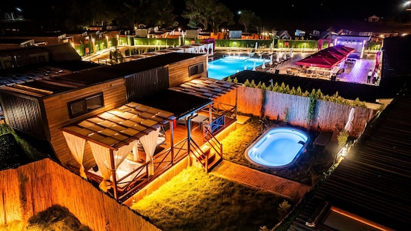 A well-lit outdoor area with a swimming pool, a hot tub, and a covered seating area. - Elite Escape Village Hotel (Catalca)