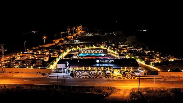 A hotel with a prominent sign, multiple parking spaces, and a well-lit entrance area.