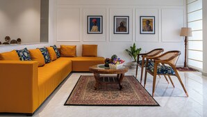 A modern living room with a sectional sofa, a coffee table, and two wicker chairs. - Alaya Stays Udgam Villas 5BHK Apartment (Dehradun)