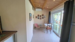 A room with a wooden ceiling, a dining area with chairs, a table, and a large window with curtains. - Charming air-conditioned studio with pool between Aix-en-Provence and Marseille (Les Pennes-Mirabeau)