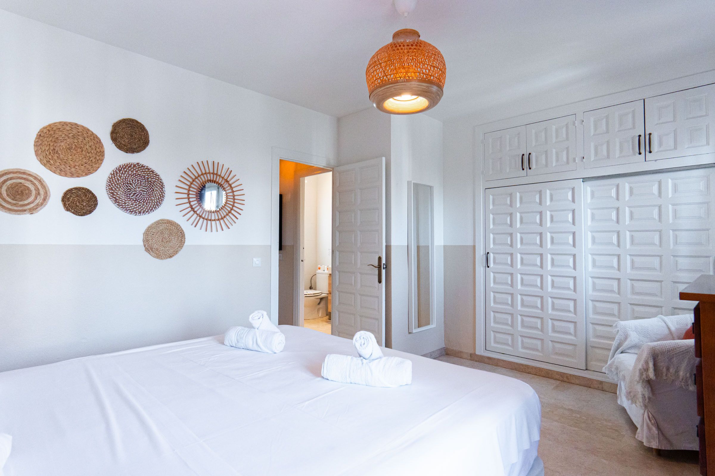 Een hotelkamer met een bed, een kledingkast en een badkamer, zichtbaar door een geopende deur.