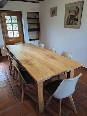 A dining area with a wooden table, white chairs, and a tiled floor.