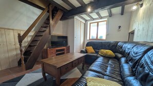 A living room with a wooden staircase, a leather sofa, a wooden coffee table, and a television on a stand. - The Otter Cottage! Vacation Rental with Indoor Pool; Chancelade Pond 500 meters away (Charensat)