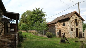 A stone building with a tiled roof, a wooden staircase, and a grassy yard with a large tree. - The Otter Cottage! Vacation Rental with Indoor Pool; Chancelade Pond 500 meters away (Charensat)