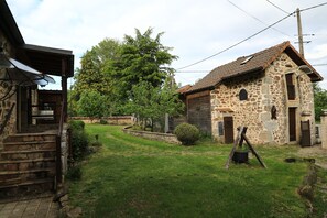 A stone building with a tiled roof, a wooden staircase, and a grassy yard with a large tree. - The Otter Cottage! Vacation Rental with Indoor Pool; Chancelade Pond 500 meters away (Charensat)