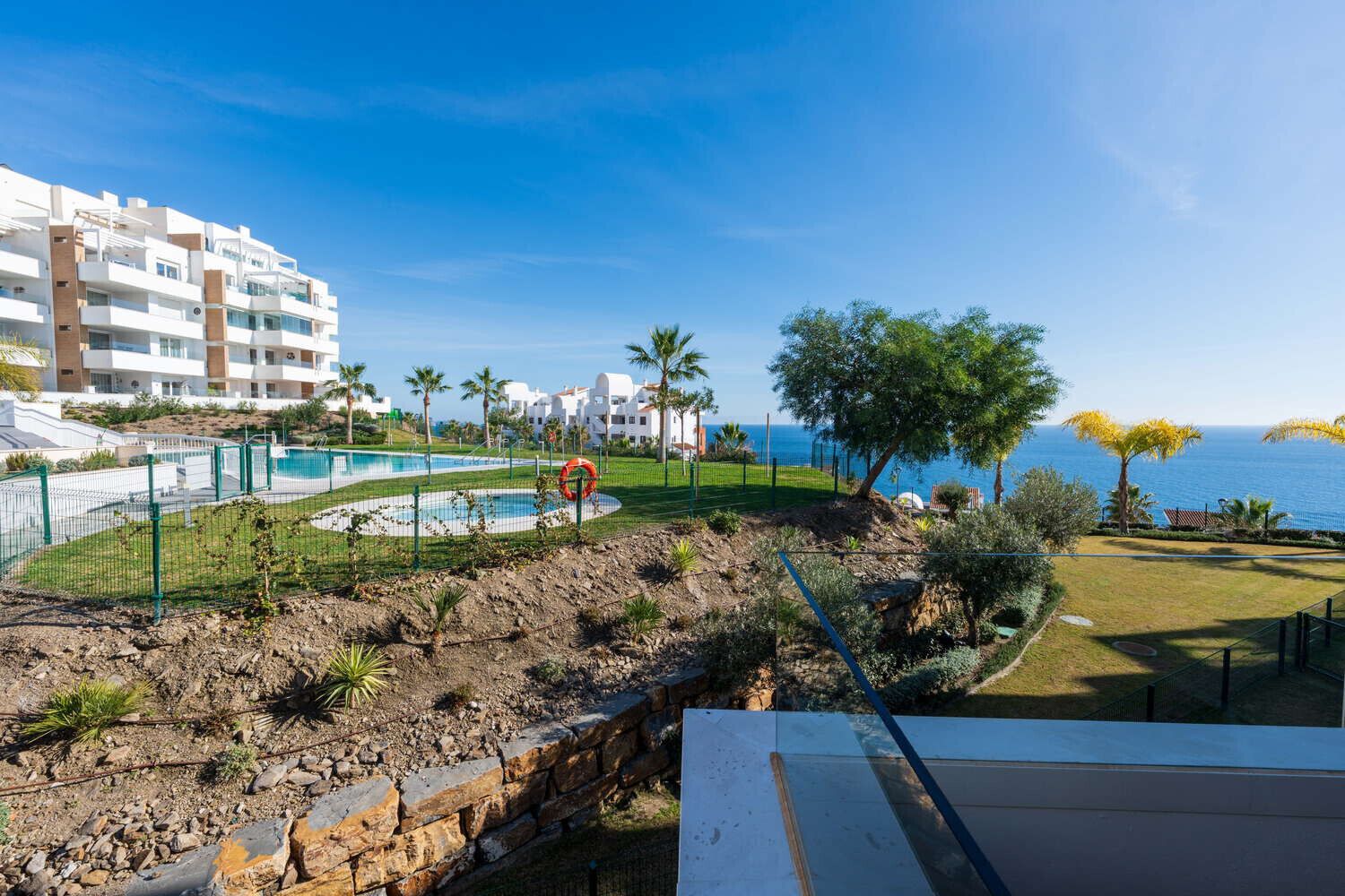 Un hotel costero con piscina, jardín rocoso y vistas al mar.