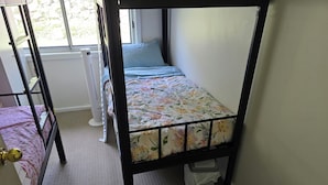 A bunk bed with a floral bedspread, a white radiator, and a window with a view of greenery. - Book a Bed in 4 Beds Mixed Dormitory (Ashcroft)