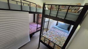 A dormitory room with bunk beds, a window with curtains, and a radiator. - Book a Bed in 4 Beds Mixed Dormitory (Ashcroft)