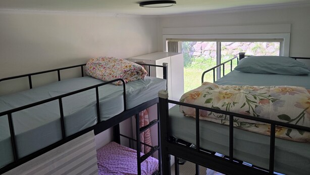 A dormitory room with bunk beds, a window, and a door. - Book a Bed in 4 Beds Mixed Dormitory (Ashcroft)
