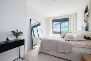 A modern bedroom with a bed, a black console table, a large mirror, and a view of the outdoors. - RDR544 - Stunning 2 Bedroom Apartment in Ipanema Homes (Mijas)