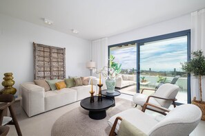 A modern living room with a sofa, chairs, a round coffee table, and a large window with a view. - RDR544 - Stunning 2 Bedroom Apartment in Ipanema Homes (Mijas)