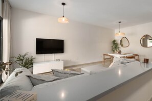 A modern living room with a large TV, a dining area, and a sofa. - RDR541 - Gorgeous 2 bed Apt. in Los Flamingos (Marbella)