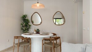 A dining area with a round table, four chairs, two wall-mounted mirrors, a hanging light fixture, and a potted plant. - RDR541 - Gorgeous 2 bed Apt. in Los Flamingos (Marbella)