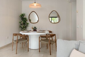 A dining area with a round table, four chairs, two wall-mounted mirrors, a hanging light fixture, and a potted plant. - RDR541 - Gorgeous 2 bed Apt. in Los Flamingos (Marbella)