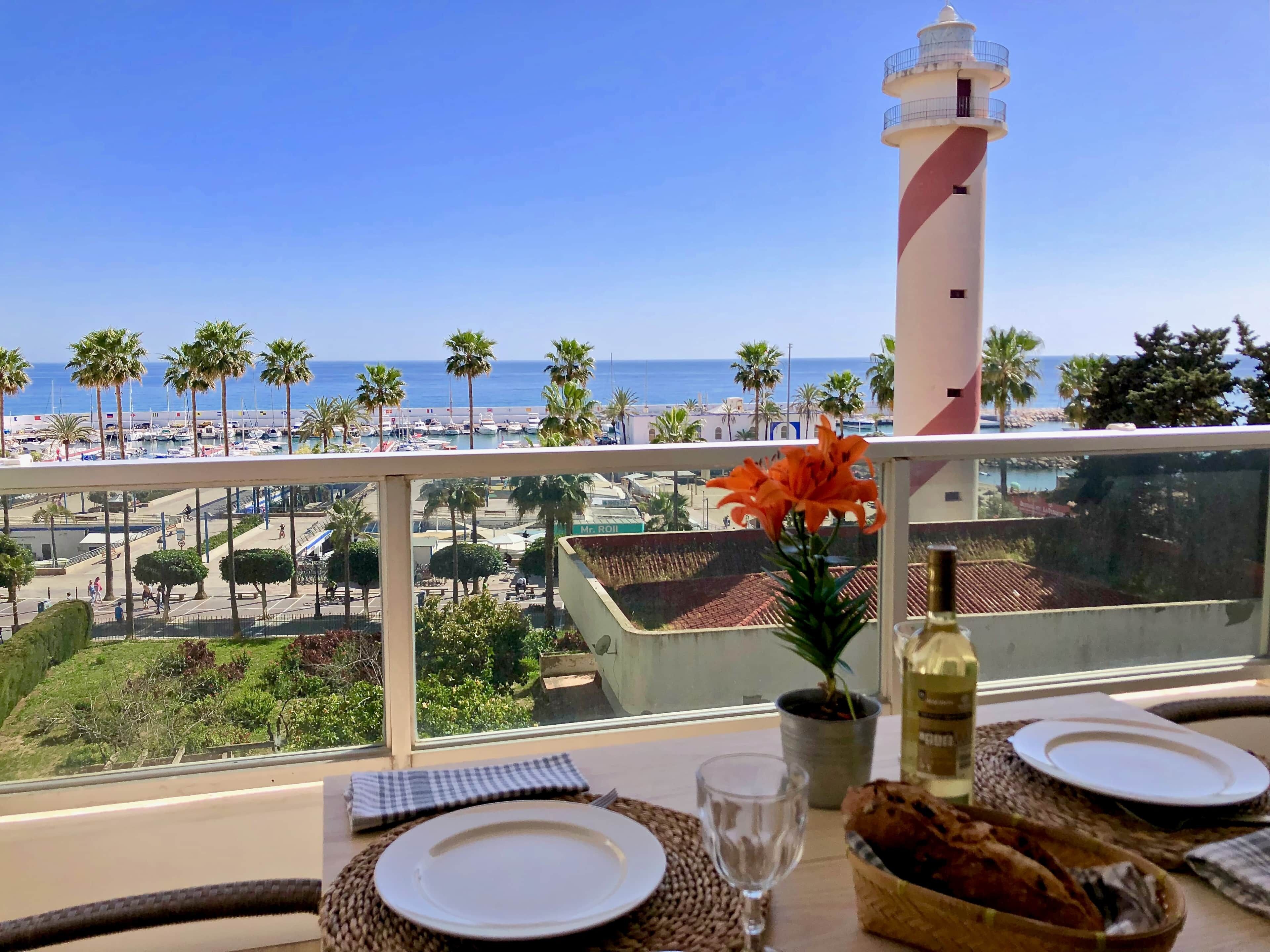 Mesa lista para comer con vista al mar y un faro.