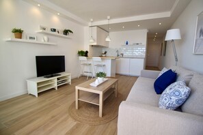 Ein modernes Wohnzimmer mit Fernseher, Sofa und Essbereich.